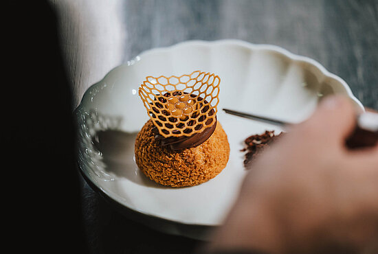 Kunstvolles Dessert mit feinem Garniernetz auf einem weißen Teller im 4 Sterne Hotel Solaria in Ischgl.